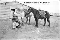 Cowboy aiming a gun, possibly on Minor Brothers ranch near Medicine Hat, Alberta.